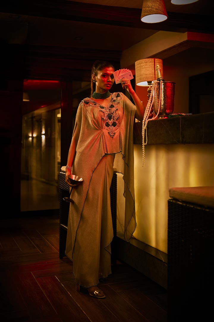 A taupe crushed fabric cape set paired with a draped skirt, featuring intricate neckline embroidery for an elegant finish.