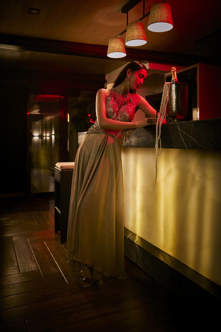 A taupe crushed fabric jumpsuit gown with intricate bead embroidery for a refined, modern silhouette.