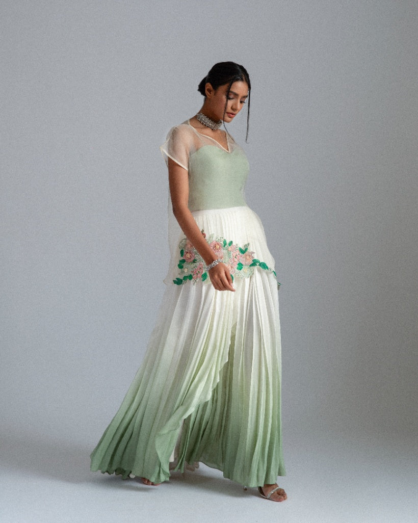 Organza top with delicate floral motifs, accompanied by a sage green bustier and an ombré-layered asymmetrical skirt. 