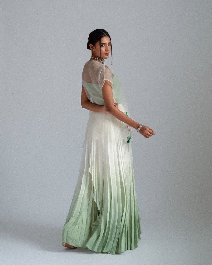 Organza top with delicate floral motifs, accompanied by a sage green bustier and an ombré-layered asymmetrical skirt. 