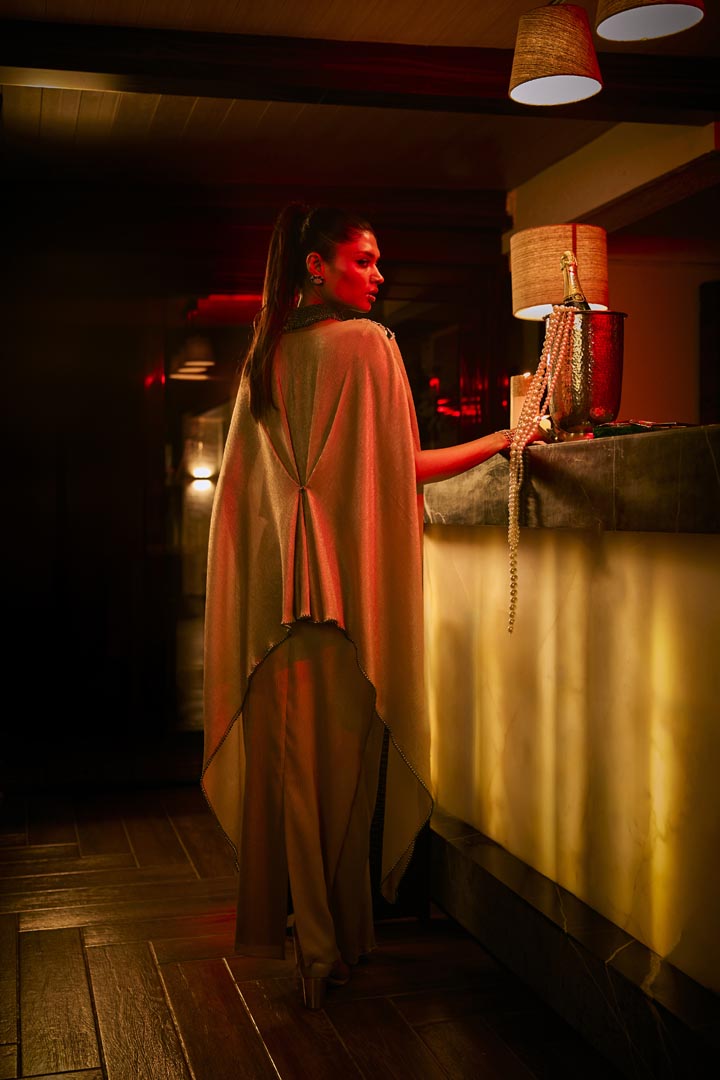 A taupe crushed fabric cape set paired with a draped skirt, featuring intricate neckline embroidery for an elegant finish.