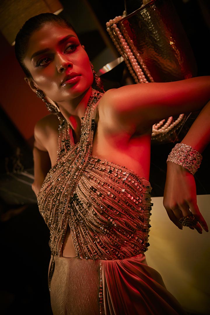 A taupe crushed fabric jumpsuit with a hand-embroidered halter neckline and satin drape detailing.