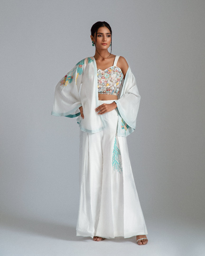 White asymmetrical jacket complemented by chanderi silk pleat flairs and a hand-embroidered net bustier.