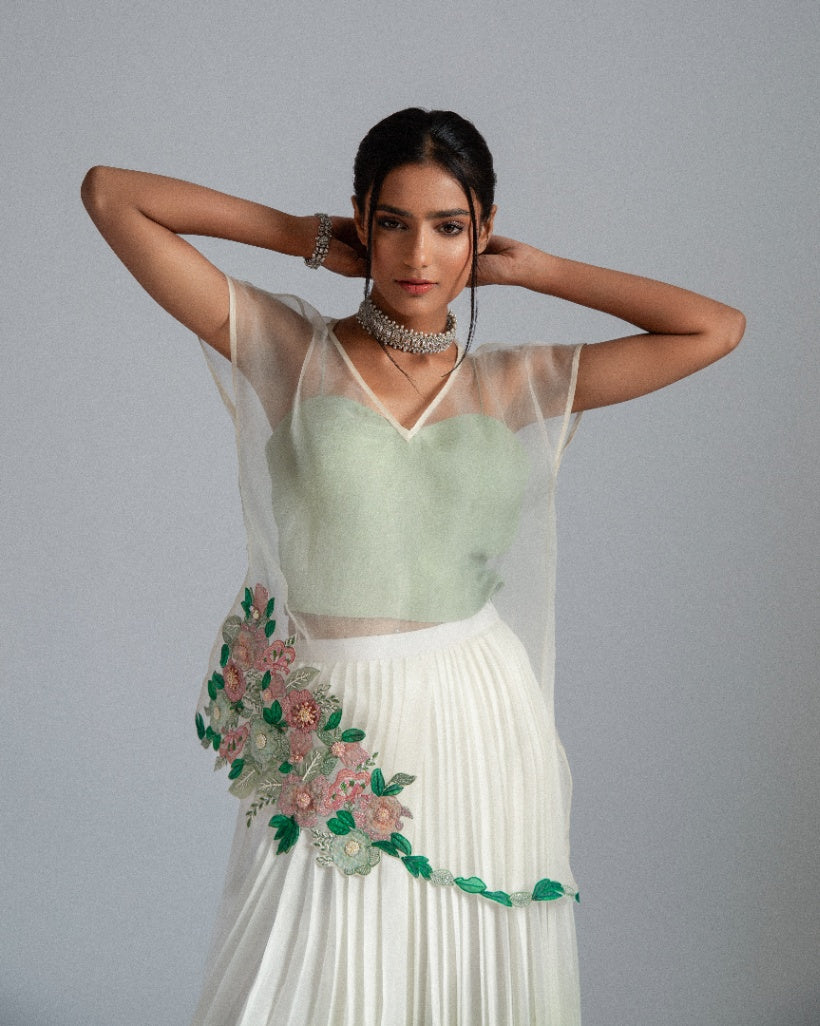 Organza top with delicate floral motifs, accompanied by a sage green bustier and an ombré-layered asymmetrical skirt. 