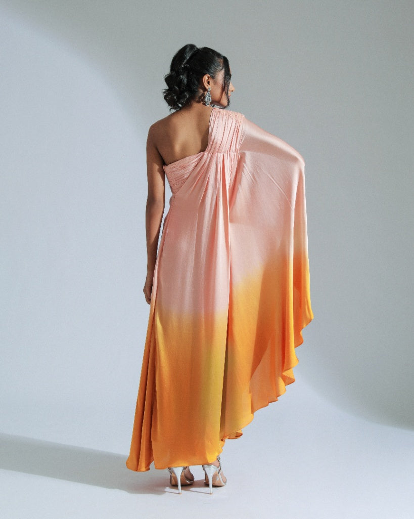 A one shoulder drape dress with a gradient from peach to vibrant orange, adorned with tone-to-tone beadwork. 