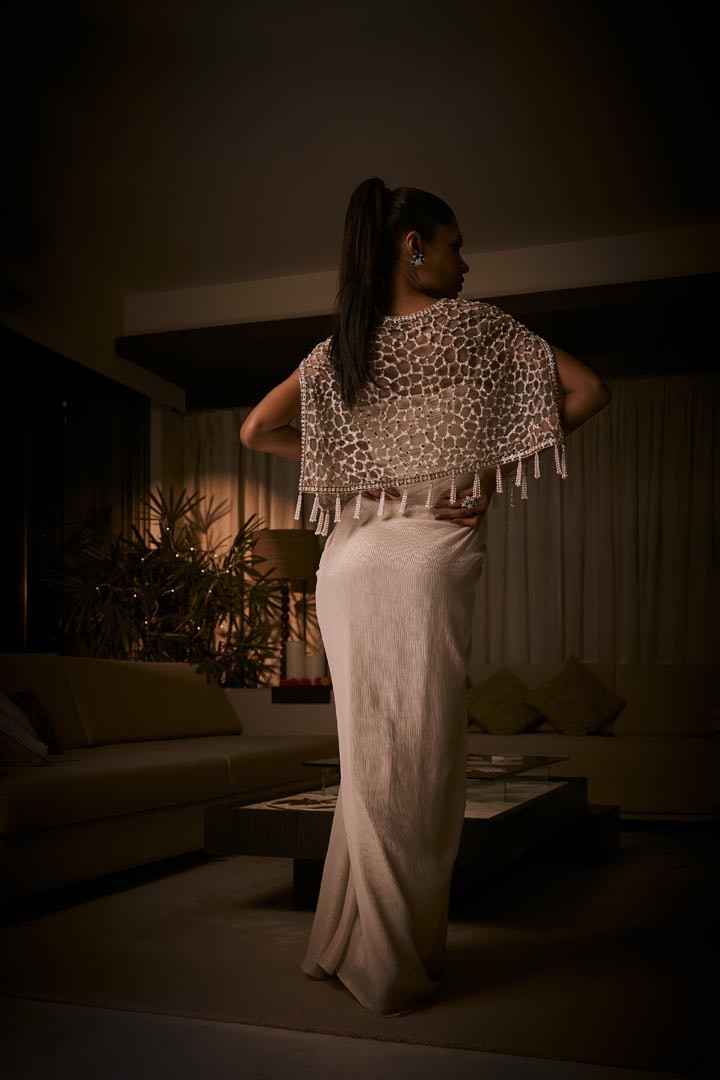 Ivory draped dress paired with a geometric embellished cape jacket, finished with  pearl tassels.