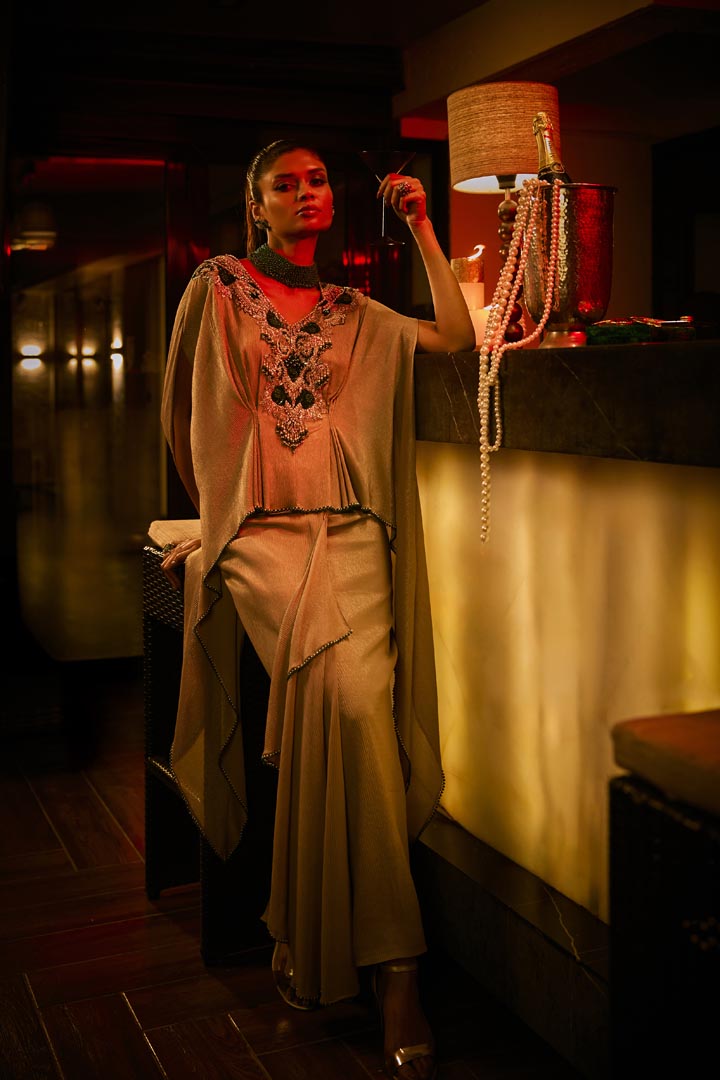 A taupe crushed fabric cape set paired with a draped skirt, featuring intricate neckline embroidery for an elegant finish.