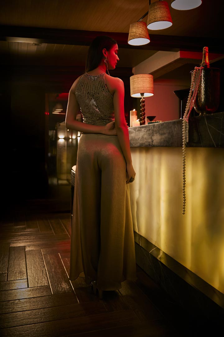 A taupe crushed fabric jumpsuit gown with intricate bead embroidery for a refined, modern silhouette.
