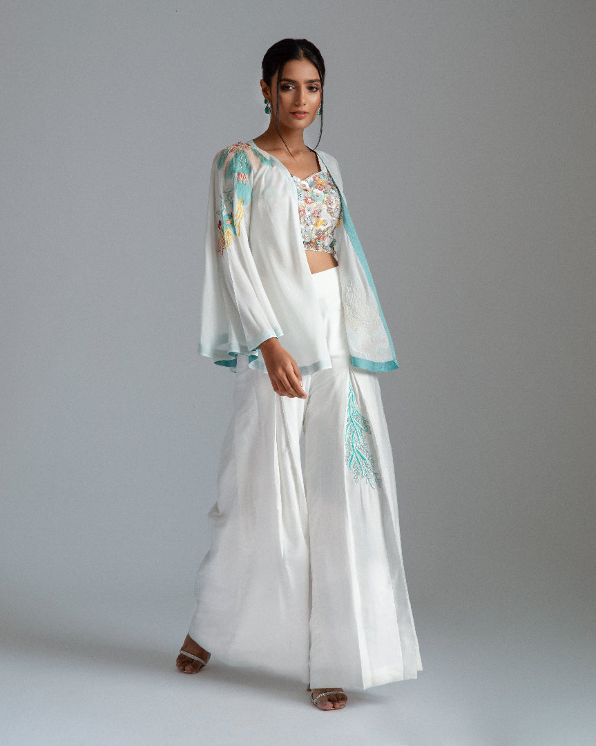 White asymmetrical jacket complemented by chanderi silk pleat flairs and a hand-embroidered net bustier.