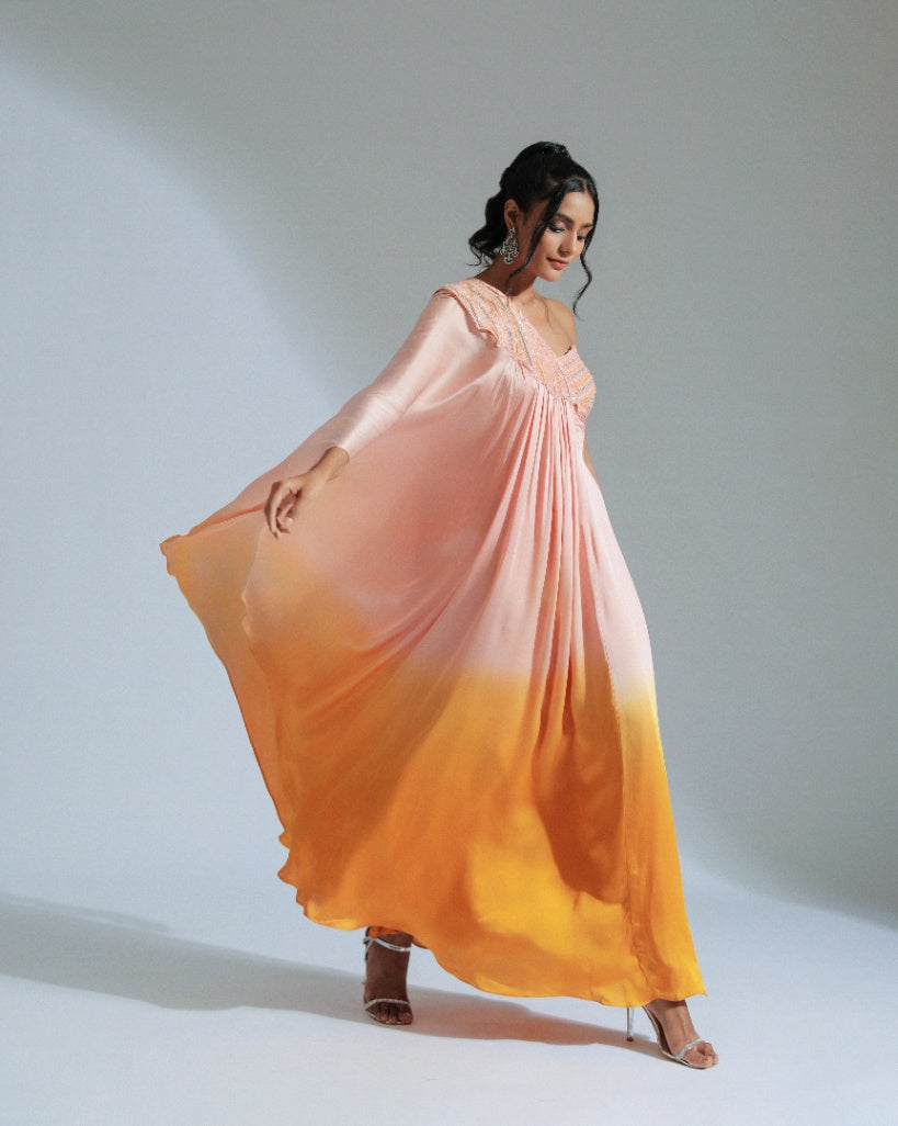 A one shoulder drape dress with a gradient from peach to vibrant orange, adorned with tone-to-tone beadwork. 