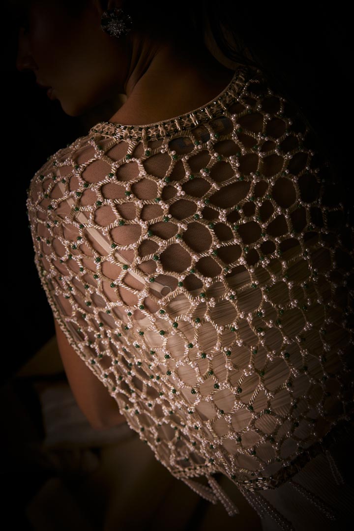 Ivory draped dress paired with a geometric embellished cape jacket, finished with  pearl tassels.