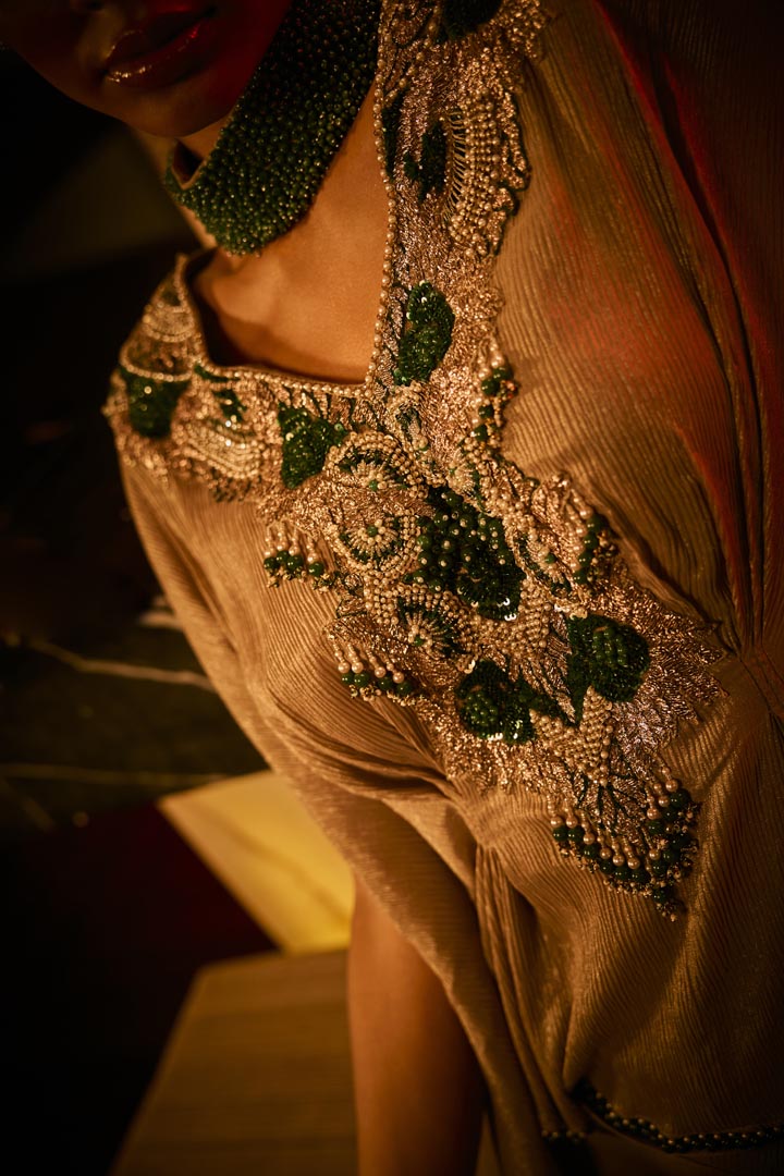 A taupe crushed fabric cape set paired with a draped skirt, featuring intricate neckline embroidery for an elegant finish.