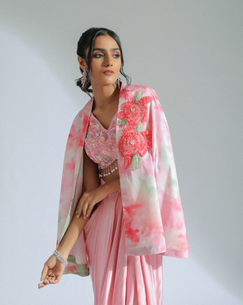 A Georgette cape in pink and sage ombré tones adorned with organza floral patterns and an inner hand-embroidered blouse with a pink modal satin lungi drape. 