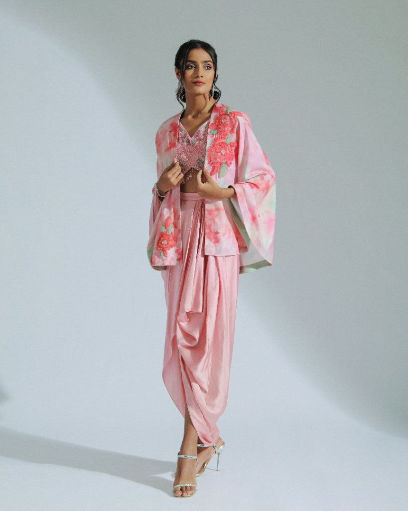A Georgette cape in pink and sage ombré tones adorned with organza floral patterns and an inner hand-embroidered blouse with a pink modal satin lungi drape. 
